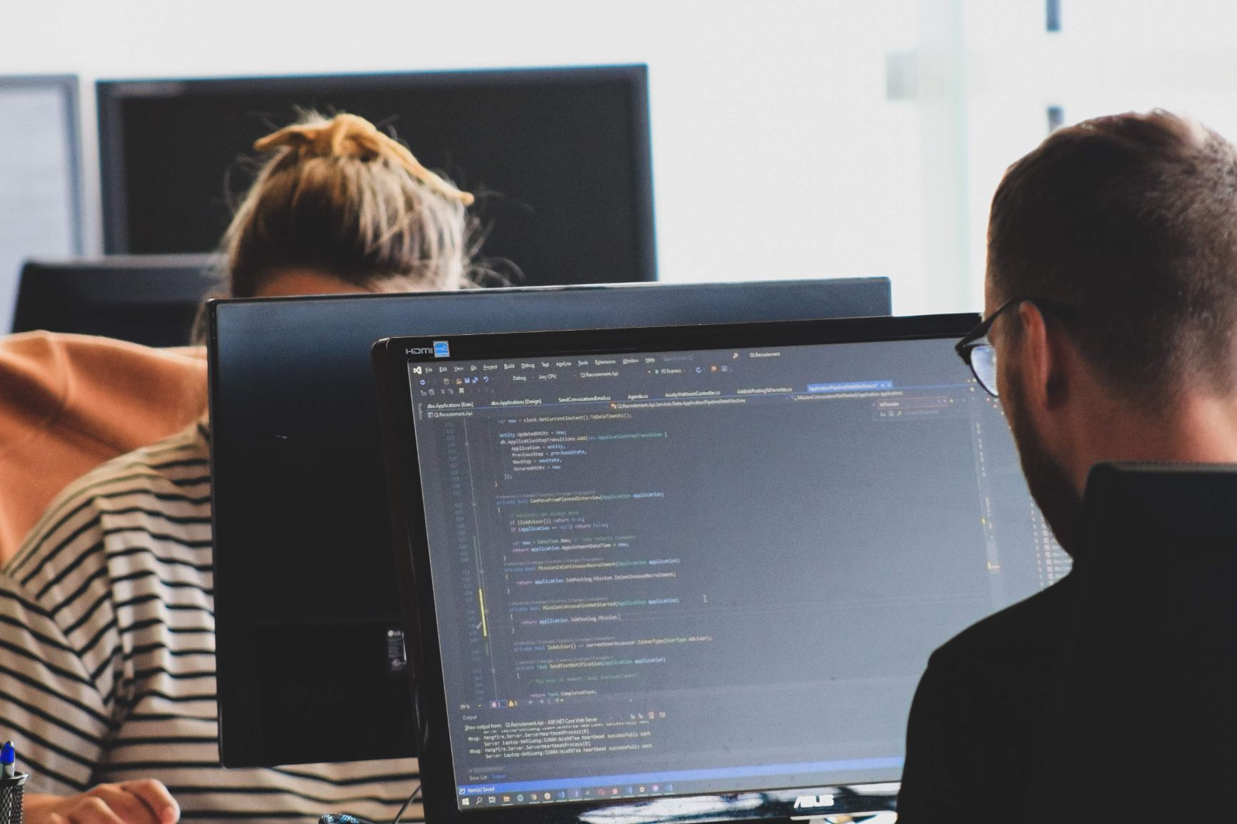 Two workers coding on their computers