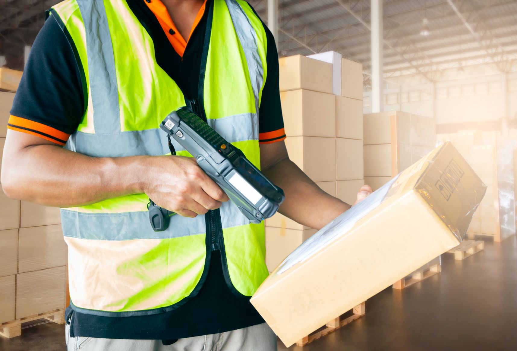 A worker using a hand-held scanner to scan a package